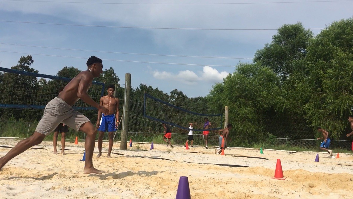 Athletes training outdoors on sand courts