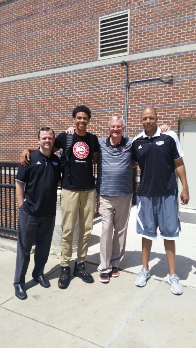 Basketball athlete standing with coaches after a recruitment visit