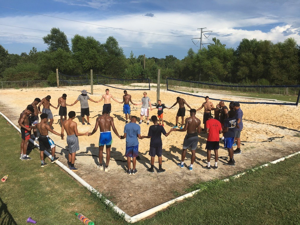Athletes standing together in prayer at an outdoor training session