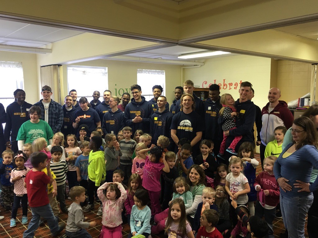 Basketball players visiting children in a community room